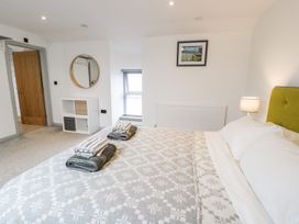 A bedroom with a bed, towels, lamp, and shelf at Cae Sam in Pentraeth