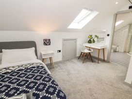 A bedroom featuring a bed with a blanket and a vanity at Cae Sam in Pentraeth