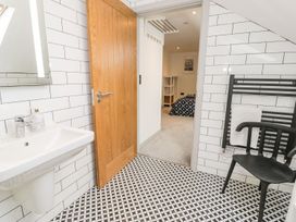 A bathroom with a sink and door at Cae Sam Pentraeth
