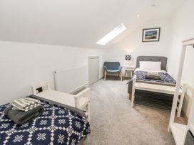 A bedroom with two beds and a chair at Cae Sam in Pentraeth