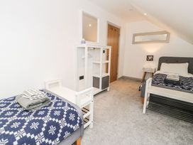 A bedroom with two beds and a shelf at Cae Sam in Pentraeth