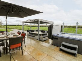 An outdoor area with a dining table, hot tub, and seating at Cae Sam in Pentraeth