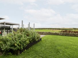 A garden with a vegetable patch and stone wall at Cae Sam in Pentraeth