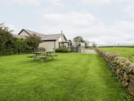 A garden with a picnic table and stone wall at Cae Sam in Pentraeth
