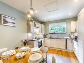 A kitchen with a dining table and white cabinets at The Whitbarrow Den in Penrith