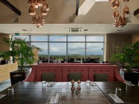 A dining room with a large window and a pink sofa at Caldew Cottage Spa in Penrith
