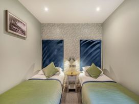 A bedroom with two beds and a bedside table at Troutbeck Cottage Spa Penrith