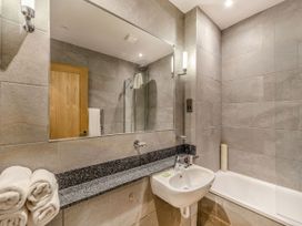 A bathroom featuring a bathtub, sink, and mirror at Troutbeck Cottage Spa in Penrith