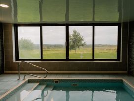 A swimming pool with a view through a large window at Troutbeck Cottage Spa Penrith