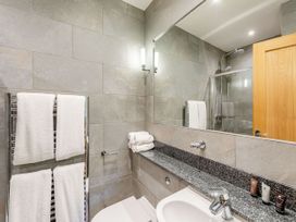 A bathroom with towels, sink, and shower at The Troutbeck Den Spa in Penrith