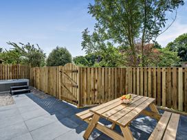 A garden with a dining table and hot tub at Klys 1.0 Spa Perranporth