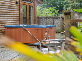 An outdoor space with a hot tub and a table with a glass and bottle at Piran Spa Lodge Pet Perranporth