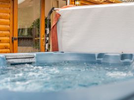 A hot tub next to a wooden cabin at Piran Spa Lodge Pet Perranporth