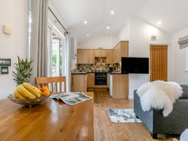 A kitchen with wooden cabinets and a dining area at Droskyn Spa Pet in Perranporth