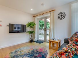 A living room with a television and doors leading to a deck at Poldark Spa Pet Perranporth