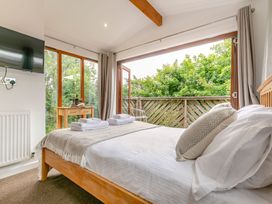 A bedroom with a bed and window doors at Treehouse Spa in Perranporth
