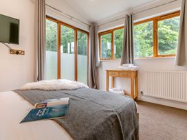 A bedroom with a bed and windows at Treehouse Spa in Perranporth