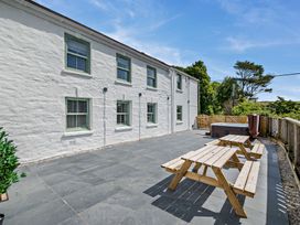 An outdoor space with picnic tables and a hot tub at The Farmhouse (Pet) in Perranporth