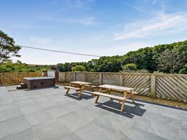 An outdoor patio with a hot tub and picnic table at The Farmhouse (Pet) Perranporth