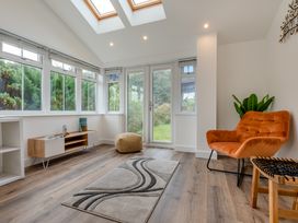A conservatory with windows and a chair at The Farmhouse (Pet) Perranporth