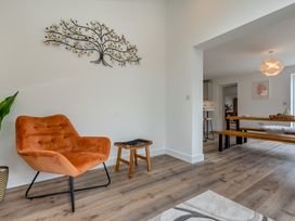 A living room with a chair and wooden table at The Farmhouse (Pet) Perranporth