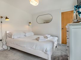 A bedroom with a bed, bedside lamps, mirror, and dresser at The Farmhouse (Pet) Perranporth