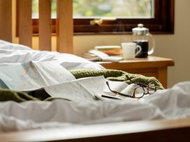 A bed with a map, book, coffee cup, and glasses at The Derwent in Slaley