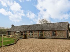 A stone building with a fence and gravel area at Long Linney in Bideford