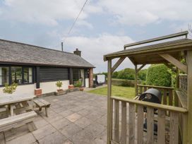 An outdoor area with a deck, table, and grill at Long Linney in Bideford