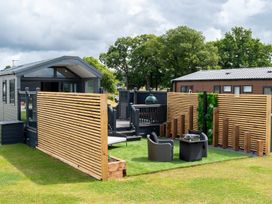 An outdoor area with a house, deck, chairs, and table at The Oasis in Great Ayton