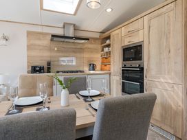 A kitchen with wooden cabinets and dining area at Leven (Pet) Great Ayton
