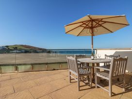 An outdoor area with a table and chairs under a parasol at 2 Burgh Island Causeway in Kingsbridge