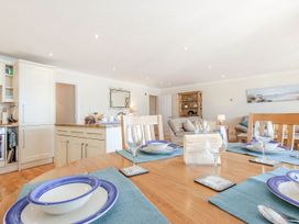 A dining room with a table set for dinner and a sofa area at 2 Burgh Island Causeway in Kingsbridge