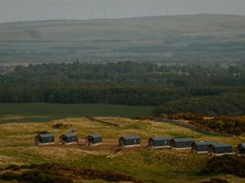View of cabins in a field with trees and wind turbines at The Grays in North Berwick