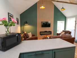 A living room with a television, sofa, and microwave at The Homestead in Moorsholm