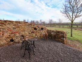 An outdoor seating area with a stone wall and a table and chair at The Homestead Moorsholm