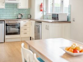 A kitchen with appliances and a dining table at 4C2 Summerleaze Garden Cottage 2 Spa in Bude