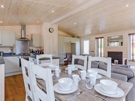An open plan living area with dining table and kitchen at Hurricane Lodge in Fair Oak