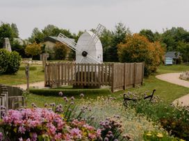 A windmill surrounded by flowers and a path at Hurricane Lodge in Fair Oak