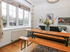 A living room with a table and benches and a vase of flowers at The White House in Bracondale