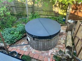 A hot tub in a garden with brick pathway at The White House in Bracondale