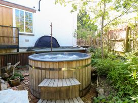 A hot tub with wooden decking in a garden at The White House in Bracondale