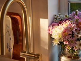 A kitchen with a faucet and a vase of flowers at The White House, Riverside Retreat Bracondale