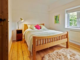 A bedroom with a wooden bed and bedside table at The White House, Riverside Retreat in Bracondale