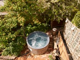 A hot tub on a brick patio surrounded by plants at The White House, Riverside Retreat, Bracondale