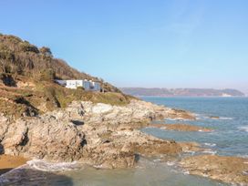 A coastline with rocks and a building at The Old Signal House in Torpoint