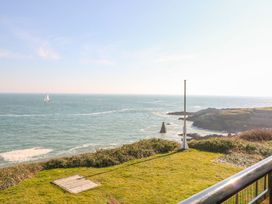 An outdoor view of the ocean with a sailing boat and a flagpole at The Old Signal House in Torpoint
