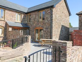 An outdoor area with a table and stone walls at Grange Cottage in Crediton