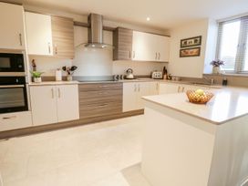 A kitchen with cabinets, oven and sink at Grange Cottage in Crediton
