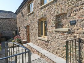 An outdoor view of Grange Cottage with stone wall and pathway in Crediton